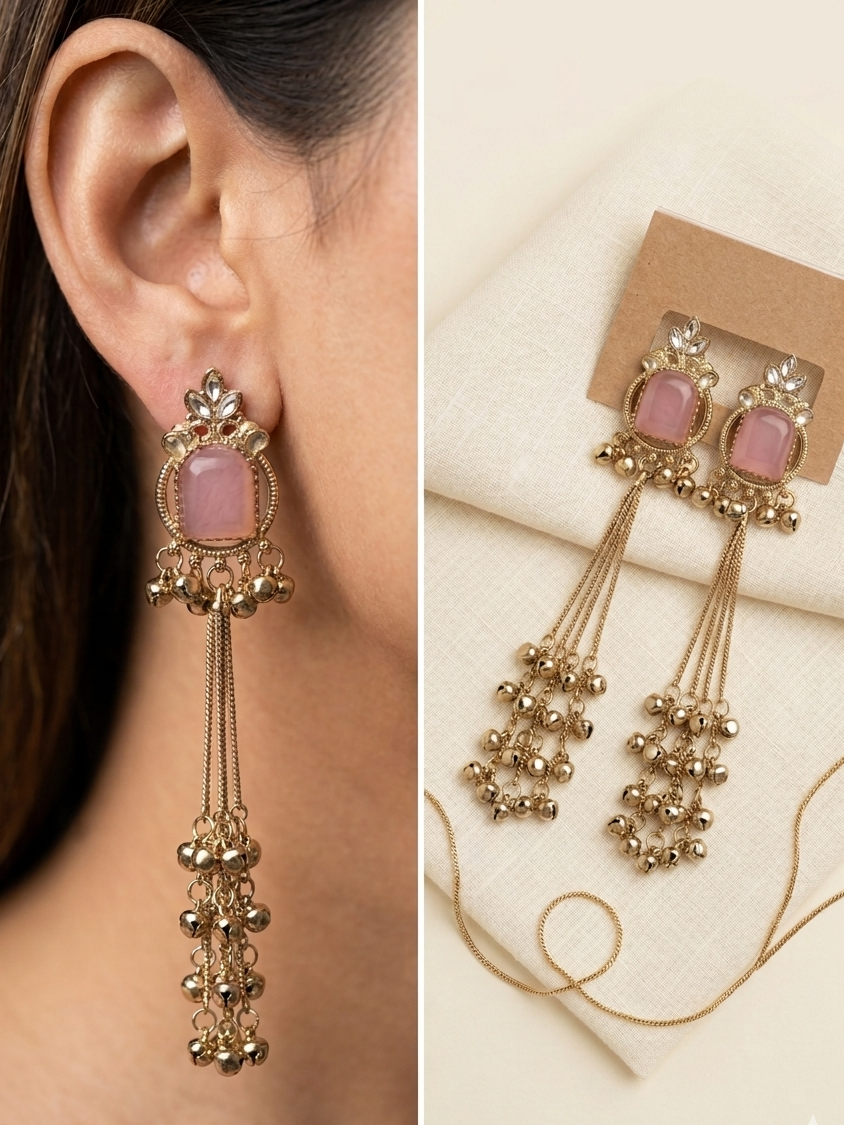 Gold earrings with pink stones worn by a person and displayed on a card.